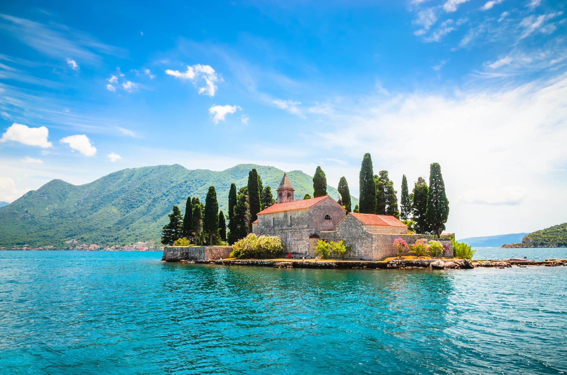St. George Island with stone church, cypress trees, and mountains in Kotor Bay, Montenegro.