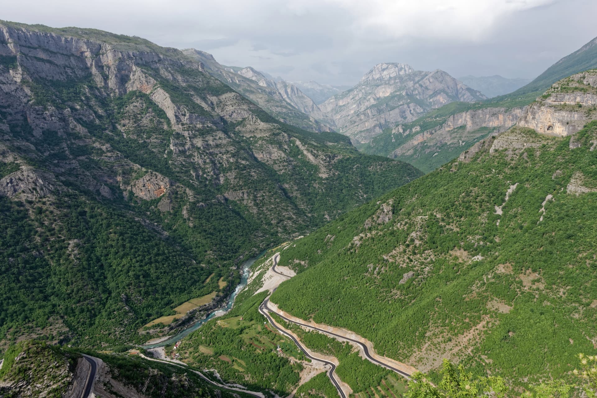 Winding road along the Cijevna River valley in the Tamara Valley, Albania, surrounded by steep, green mountains.