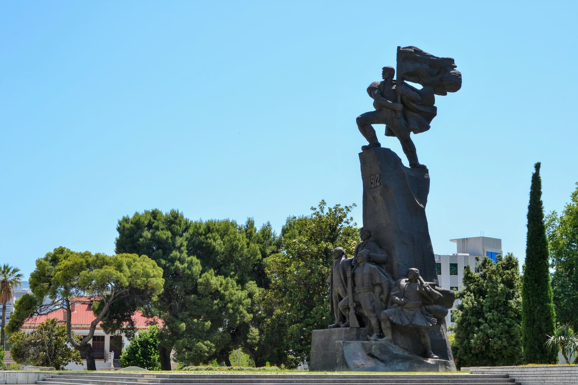 Monument of Independence in Vlore, Albania with figures holding a flag under a clear blue sky.