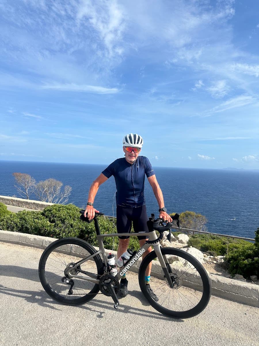 Cyclist with Cannondale road bike standing on coastal road overlooking the sea