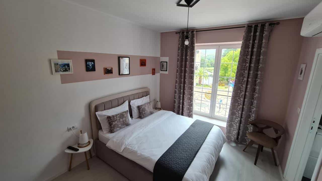 Bedroom with large bed, framed art, and balcony door view of greenery